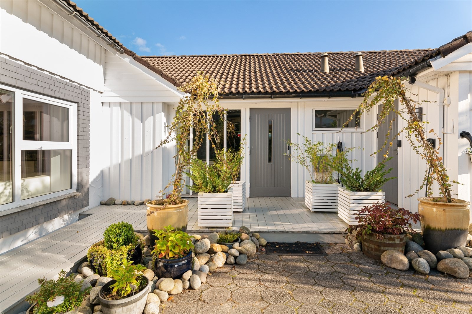 Koselig inngangsparti med platting fra gårdsrom. Gårdsrom foran garasje og bolig - til flere biler. Galleribilde