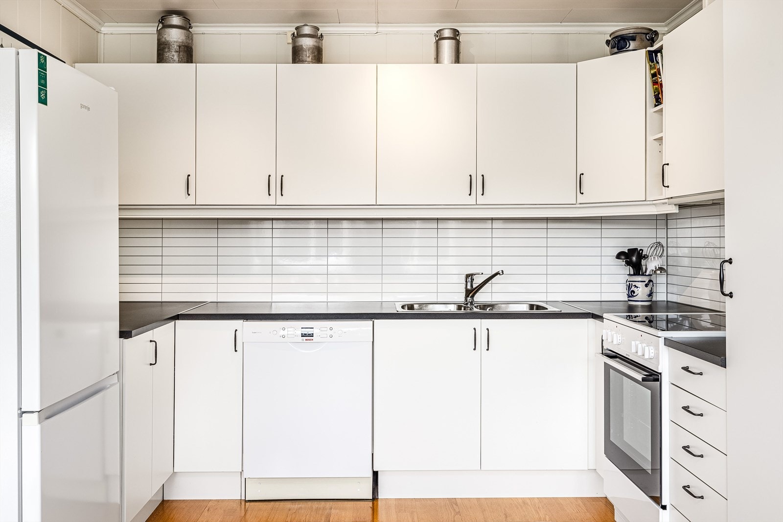 Kjøkkeninnredning hovedsakelig fra byggeår med glatte fronter. Laminat benkeplate med kitchenboards i benkeryggen. Plass til frittstående hvitevarer som kjøl-/fryseskap, komfyr og oppvaskmaskin. Galleribilde