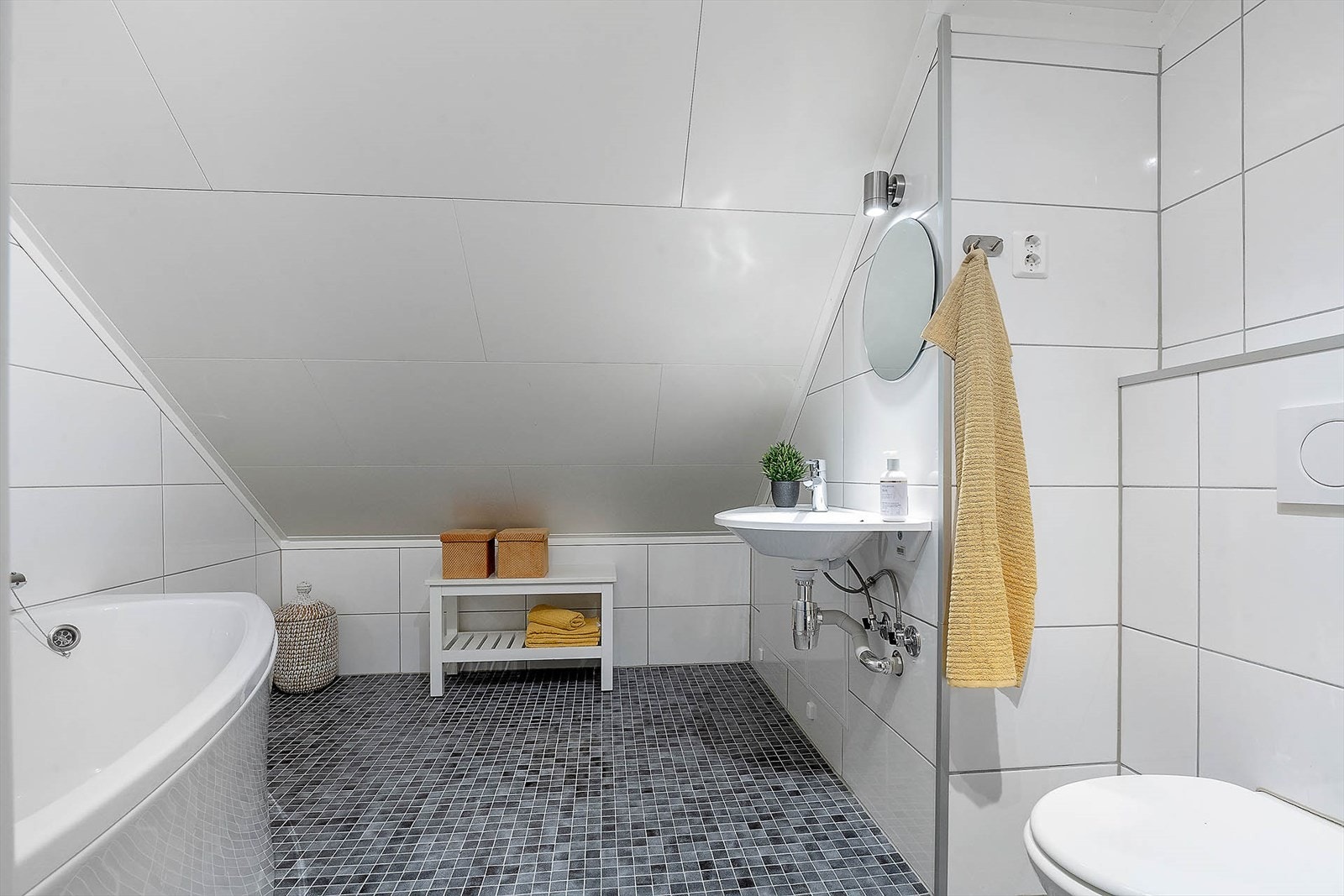 Helfliset bad med vegghengt toalett, badekar og servant med speil. Galleribilde