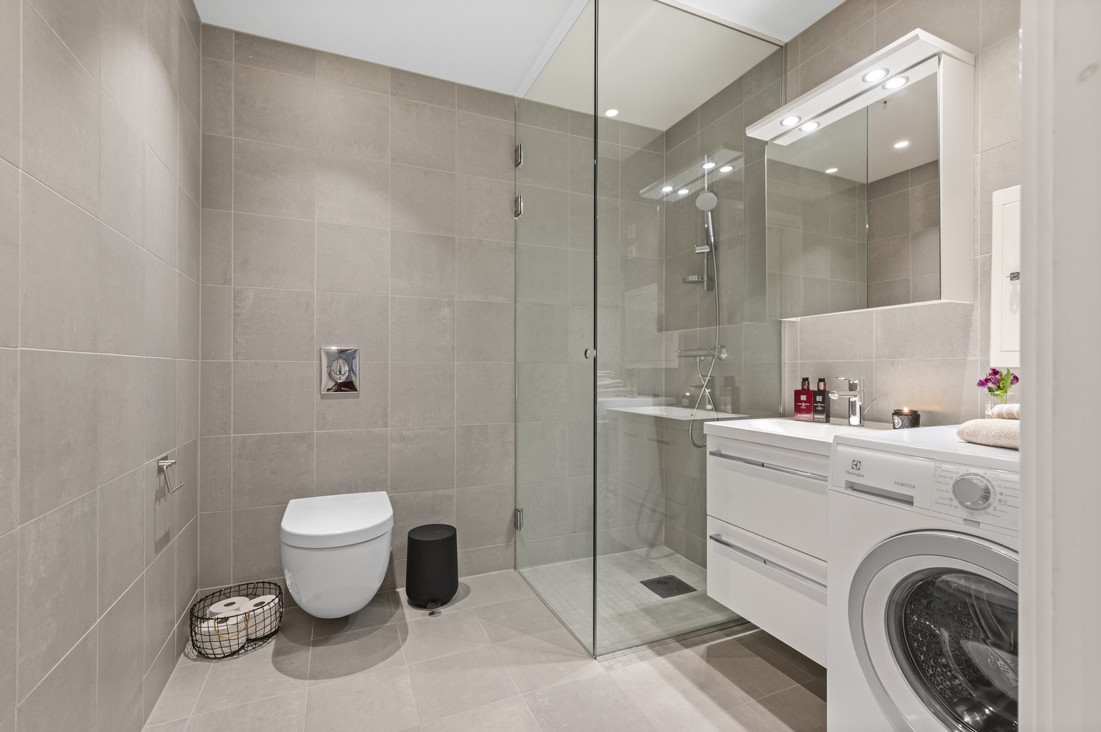 Stort og lekkert, flislagt bad med gulvvarme. Dusjløsning med skjermvegg i herdet glass, vegghengt toalett og servant med underskuffer. Galleribilde