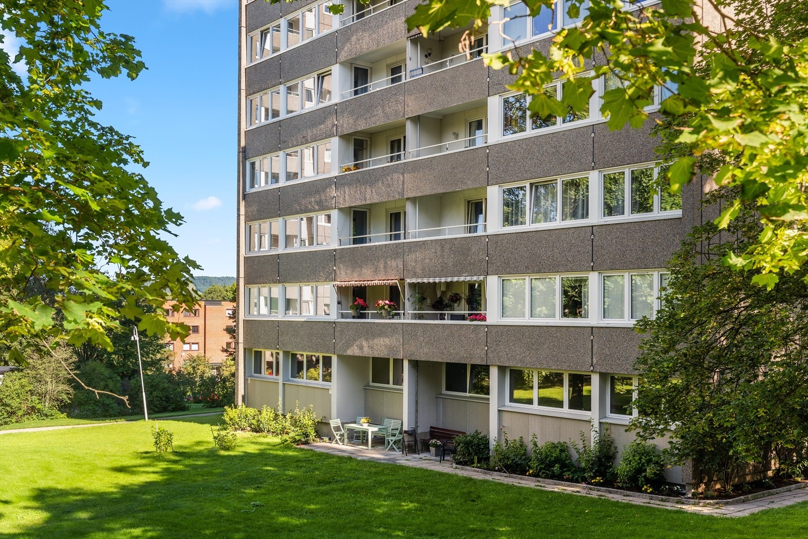 Store, fine grøntområder med plen, beplantning og sittegrupper. Galleribilde