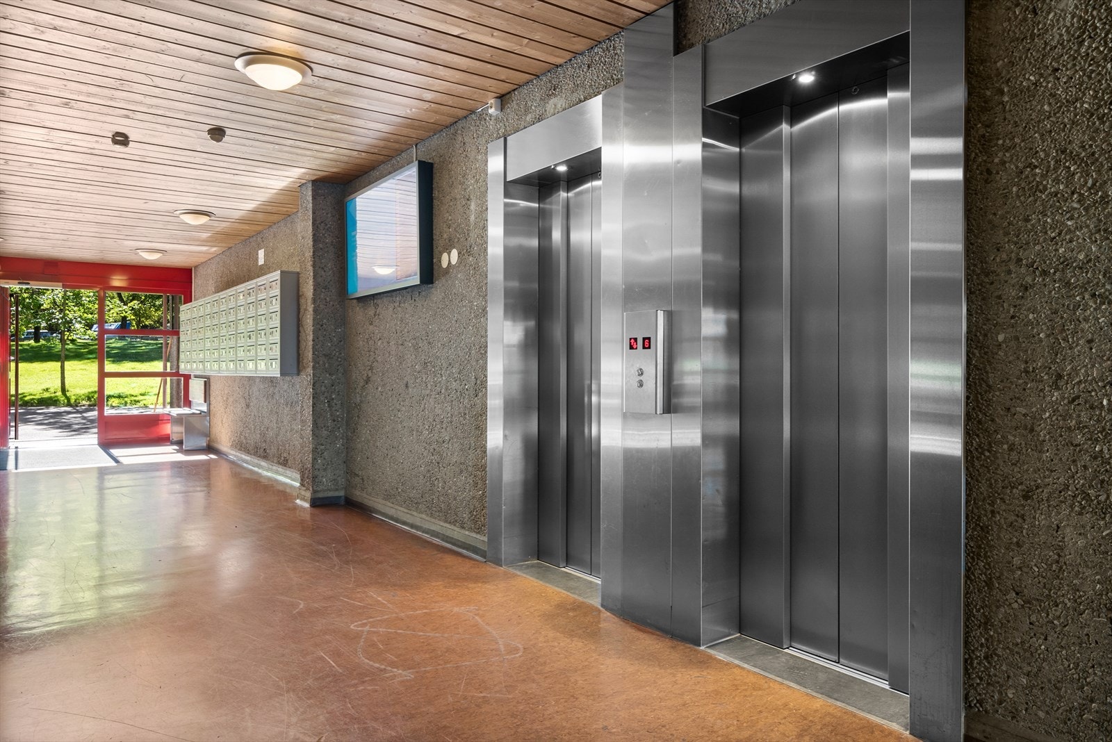 Felles inngangsparti med informasjonstavle og to heiser. Galleribilde