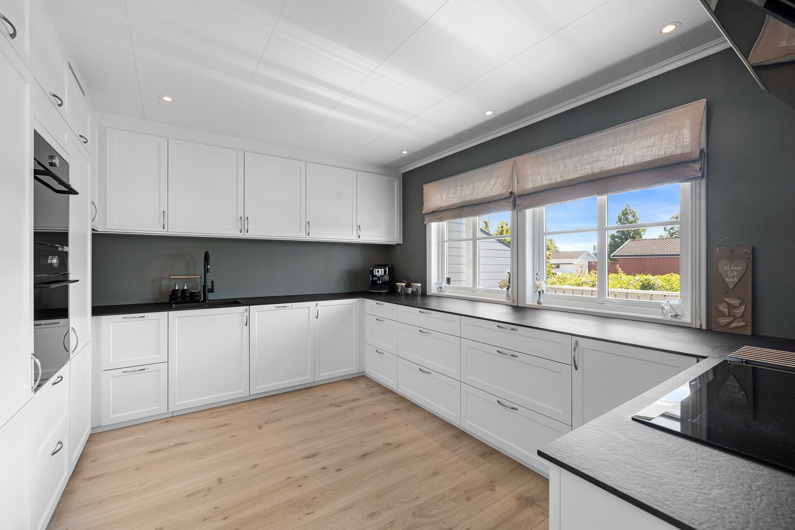 Kjøkkeninnredningen har hvite fronter og sort benkeplate. Galleribilde