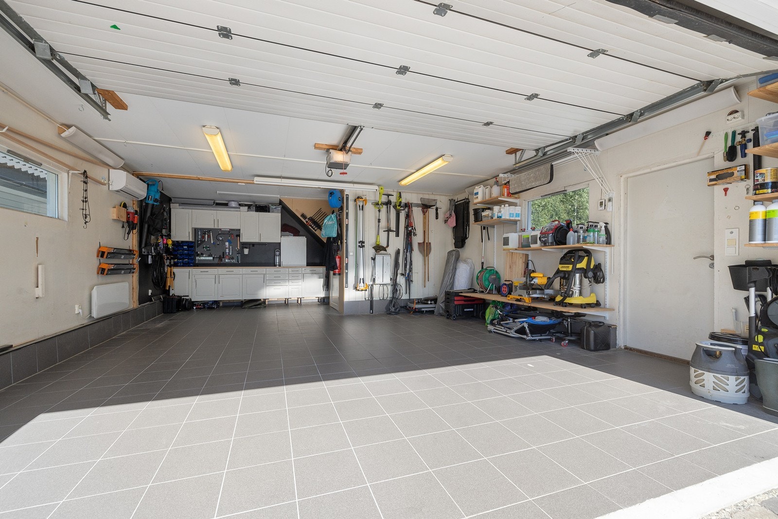 Romslig garasje med god plass til lagring av utstyr. Flislagt gulv i garasje. Galleribilde