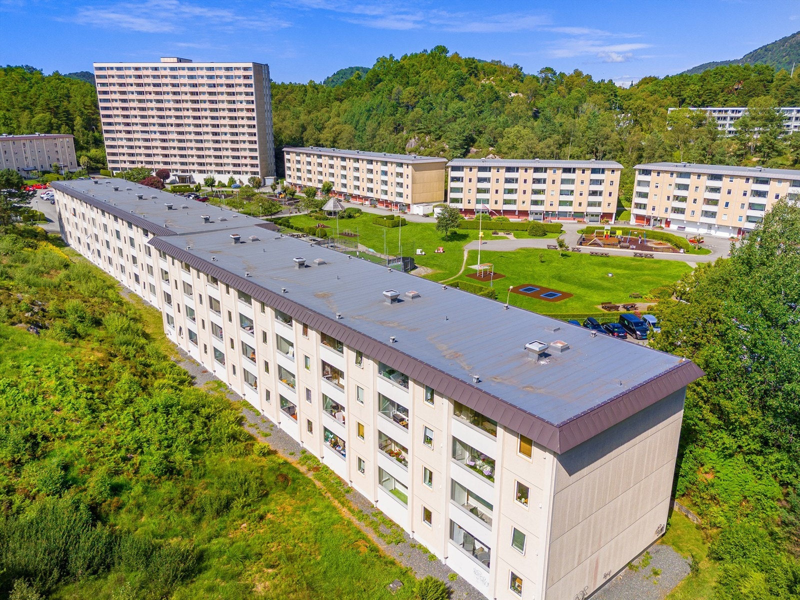 Dronefoto av blokkens fasade med balkonger med nabolaget i bakgrunnen Galleribilde