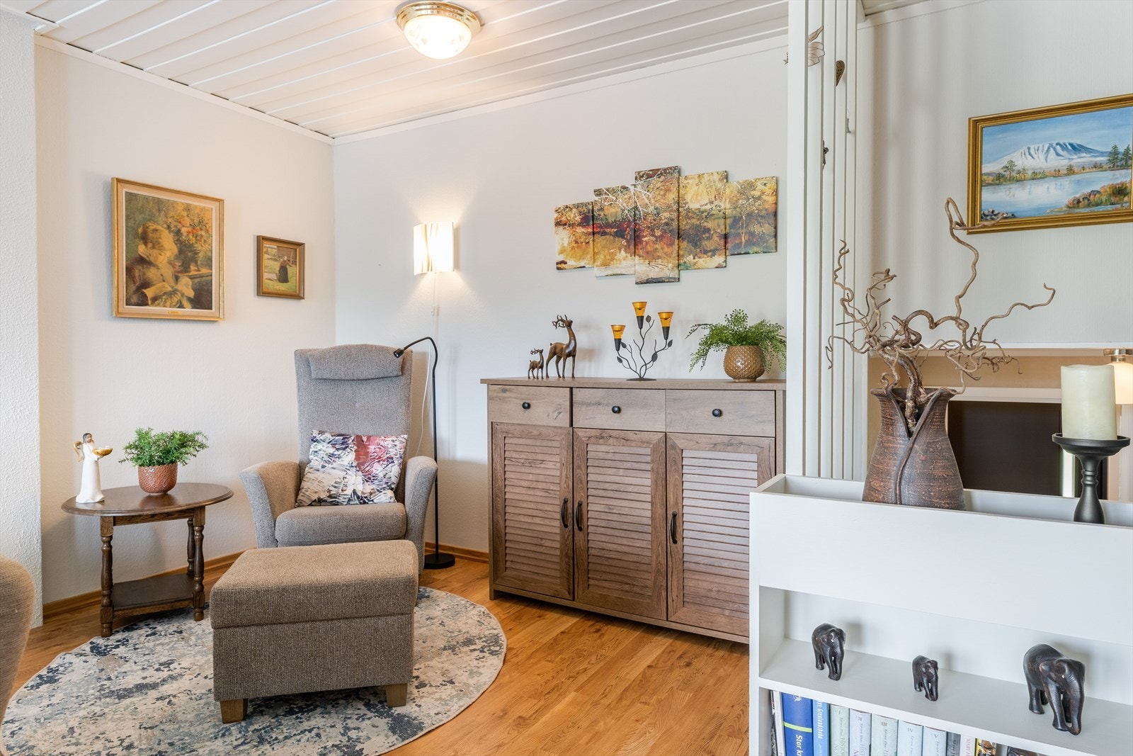 Lyse, velholdte overflater, med laminat på gulv og malt tapet på vegger, samt malt panel i tak. Galleribilde