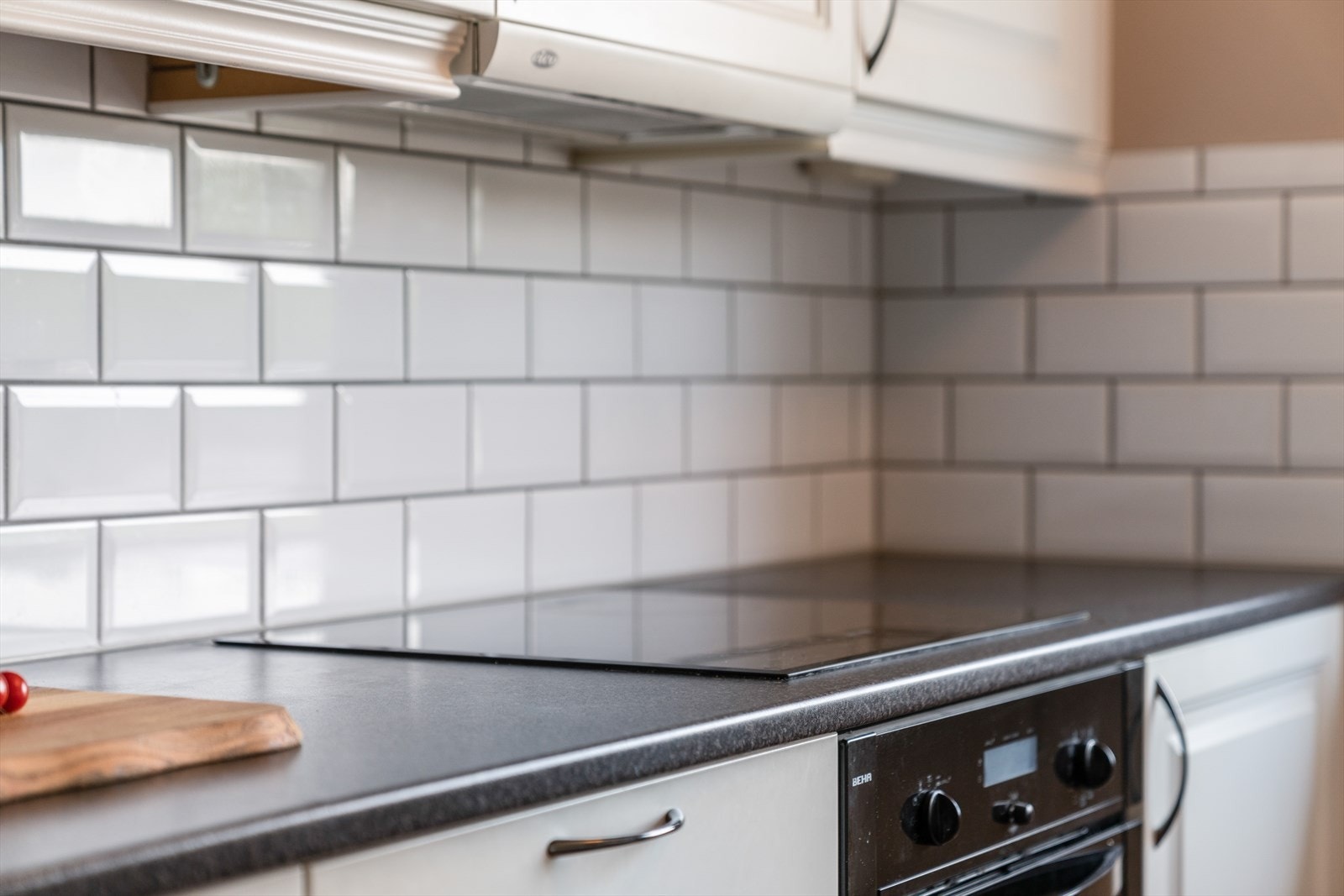 Flis på vegg over laminat benkeplate med gode arbeidsflater, nedfelt induksjonstopp og nedfelt stålvask med skyllekum. Galleribilde