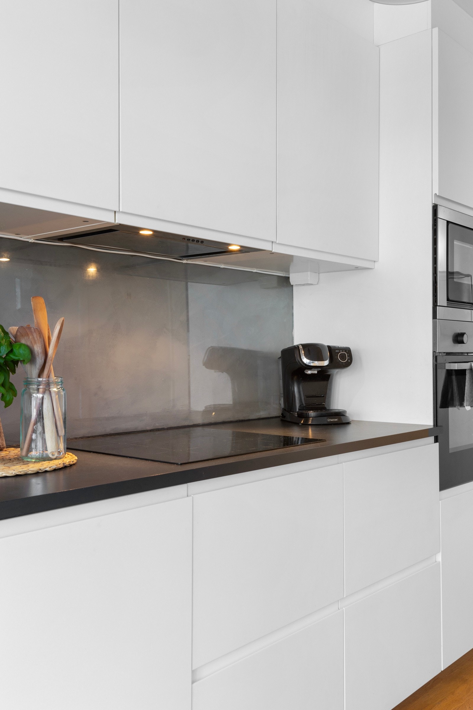 Hvite, slette fronter og glassplate over laminat benkeplate. Galleribilde