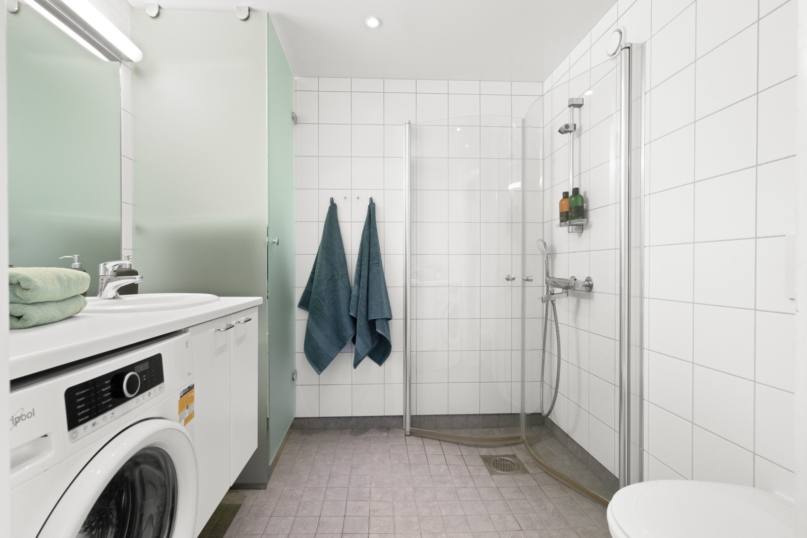 Stort praktisk baderom med tørkeskap og opplegg for vaskemaskin. Galleribilde