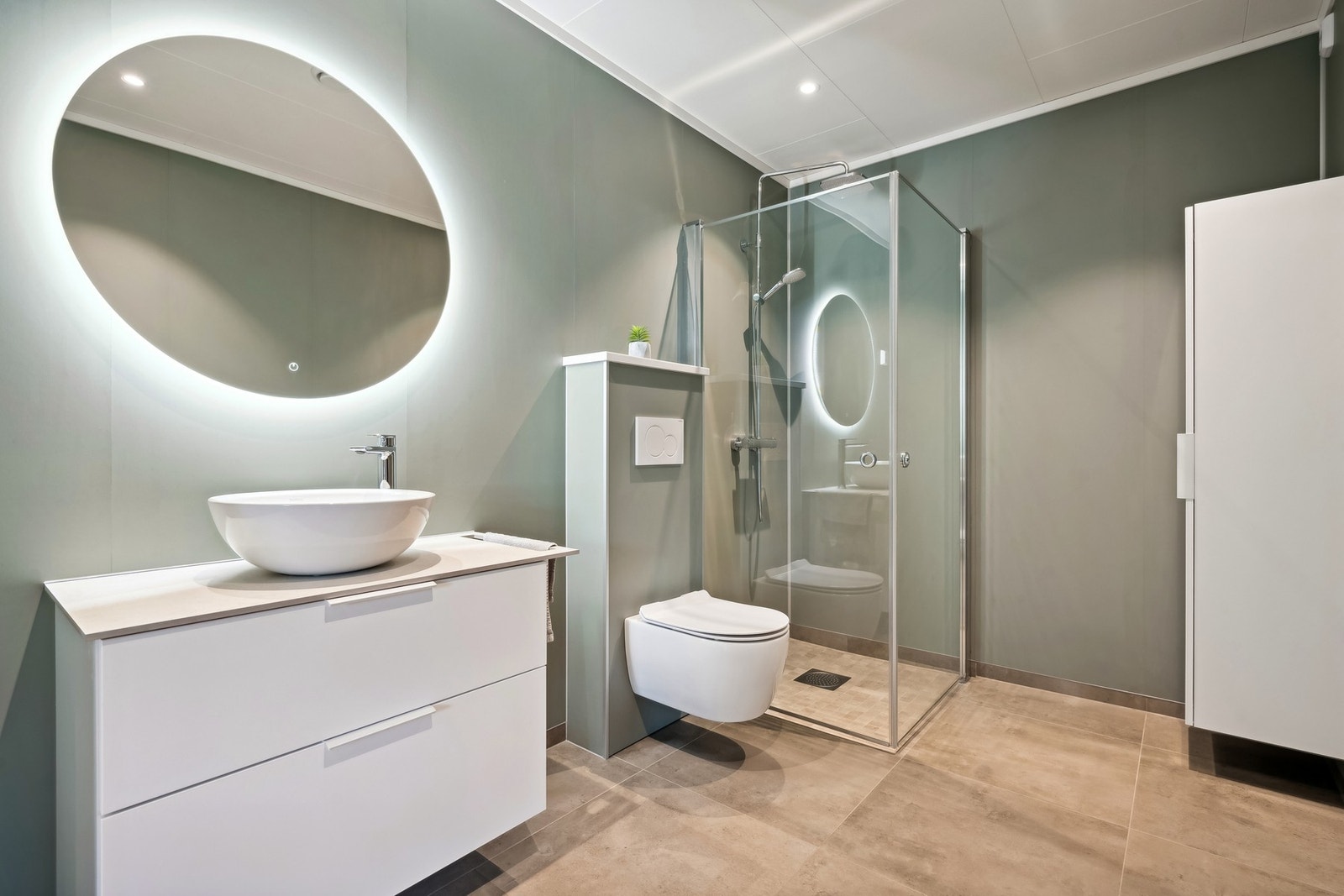 Bad med varmekabler i gulv, veggmontert toalett, nedfelt servant og dusjhjørne med regndusj. Galleribilde