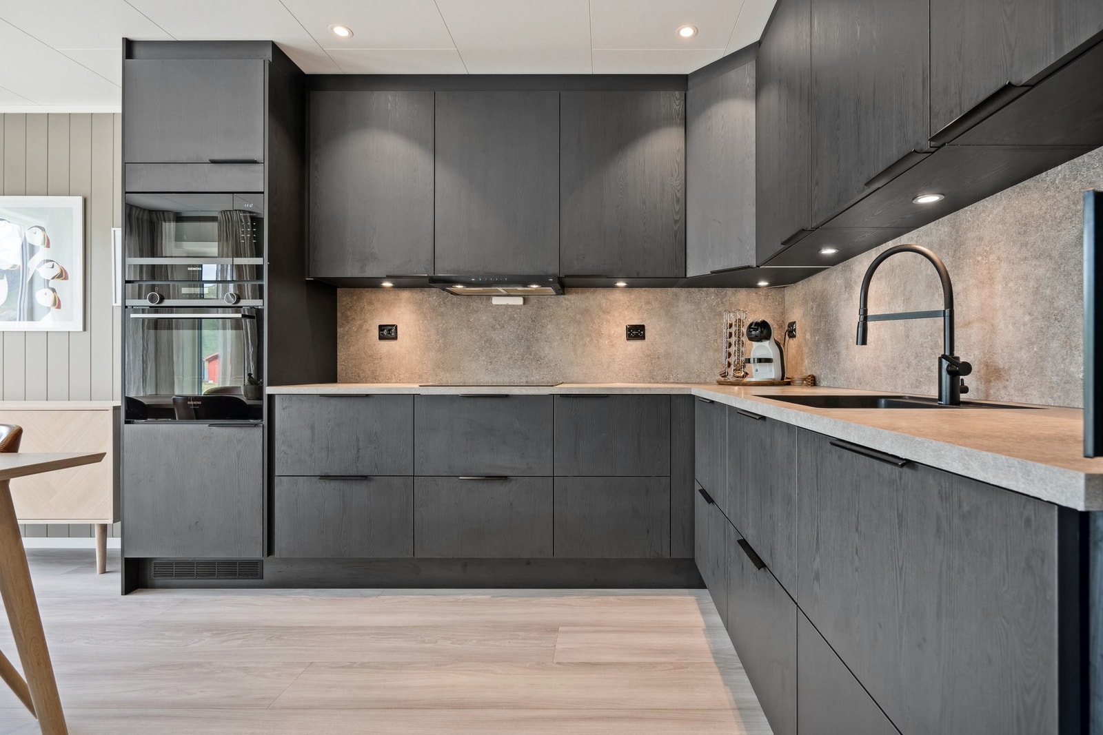 Moderne kjøkken med glatte fronter og integrerte hvitevarer. Downlights i både tak og under overskapene. Galleribilde