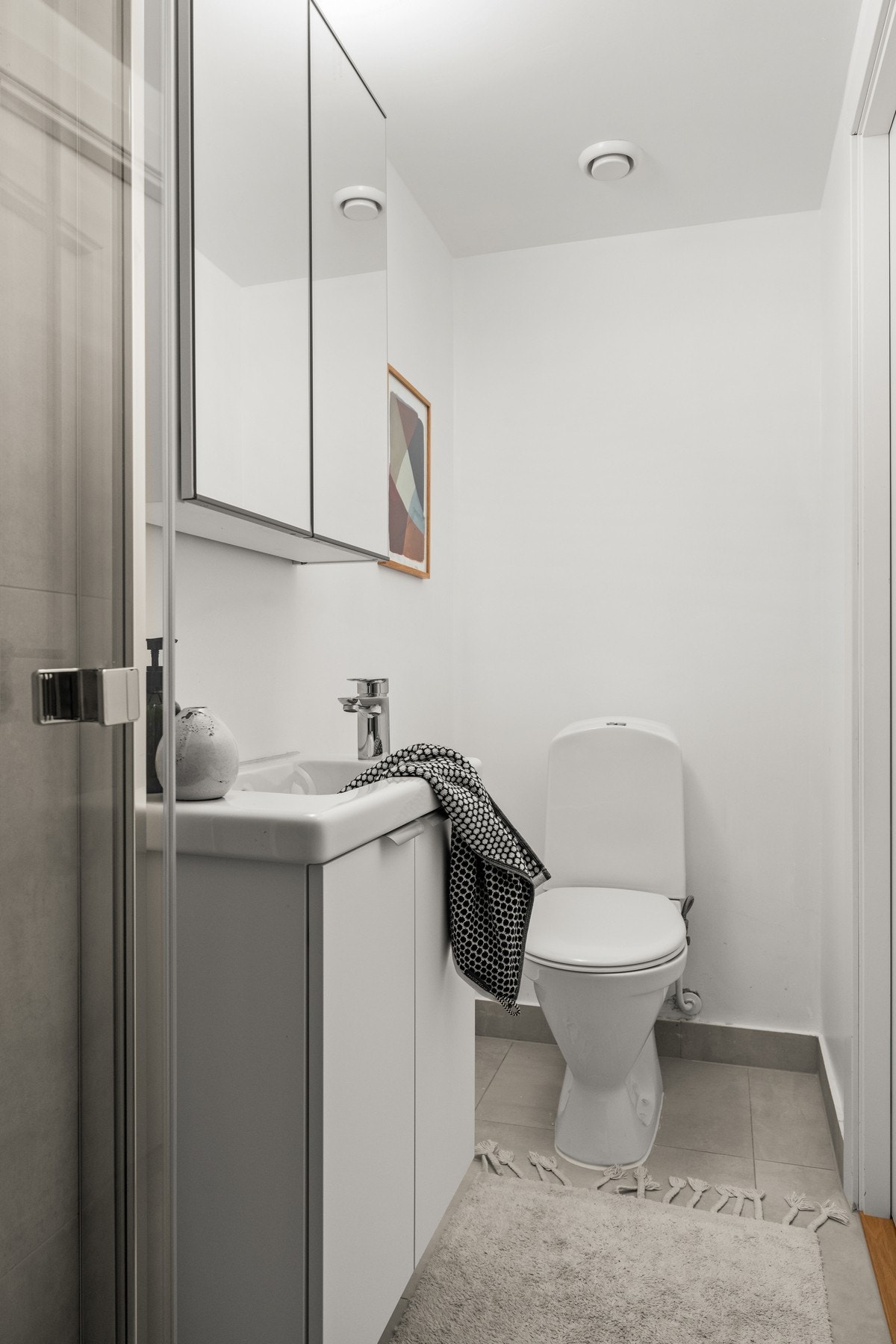 Badet inneholder dusjhjørne, servant med innredning, speilskap og toalett. Galleribilde