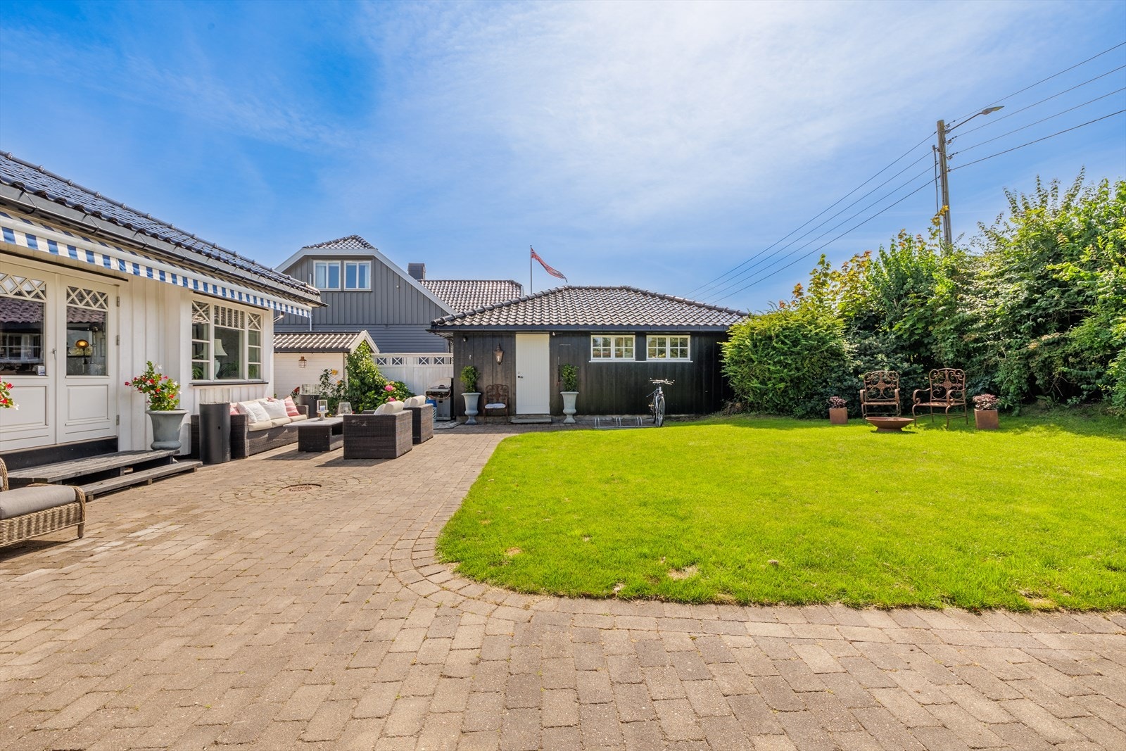 Tomten er pent opparbeidet med belegningsstein i store deler av gårdsplassen, hyggelig plenareal og diverse trær- og prydbusker. Galleribilde