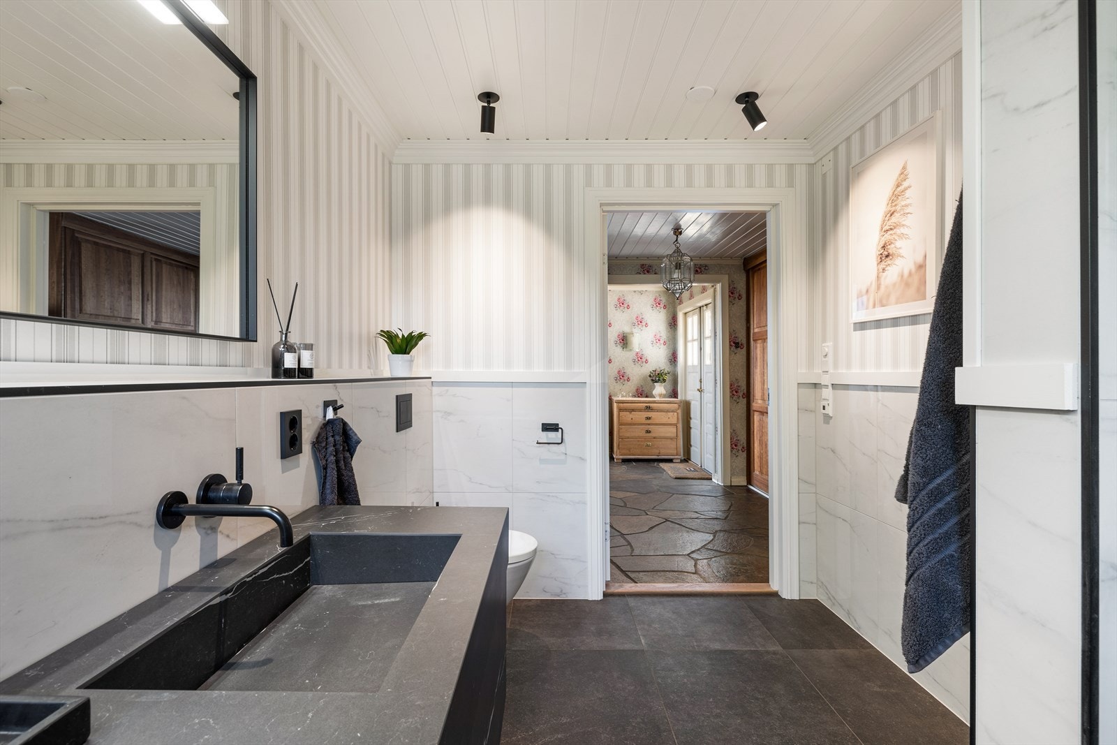 Badet har særdeles lekre fliser på gulv og vegger, og er utstyrt med vegghengt toalett, innredning med to servanter, dusj/vegger, samt opplegg til vaskemaskin. Galleribilde