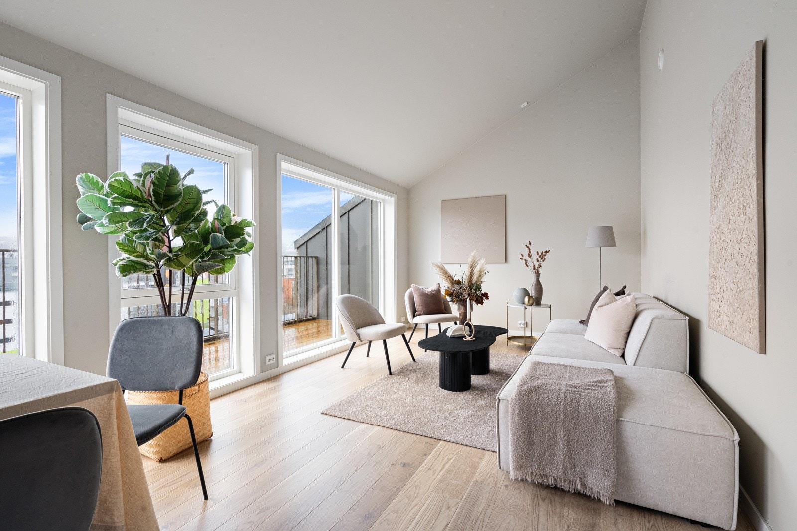 Stuen i leiligheten har fin takhøyde og vinduer som strekker langs hele ytterveggen Galleribilde