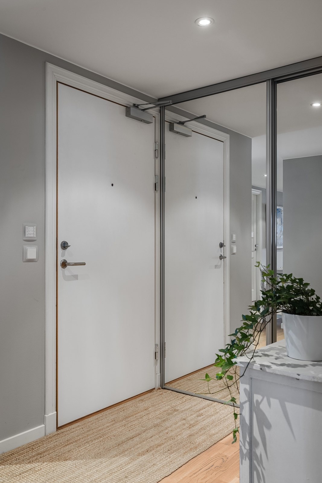 Du kommer inn i entréen hvor det er montert skyvedørsgarderobe med speilfronter. Galleribilde