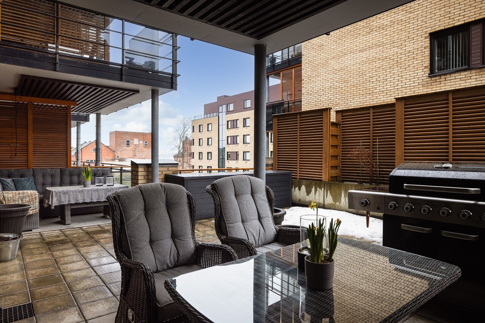 Stor delvis overbygd terrasse med plass til flere sittegrupper. Det er innsyn mot borettslagets atrium. Galleribilde