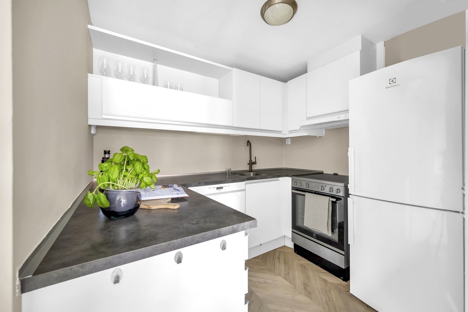 Stilsikker innredning fra byggeår med glatte, hvite fronter og benkeplate i laminat. Det er godt med lagringsplass i skap og skuffer Galleribilde