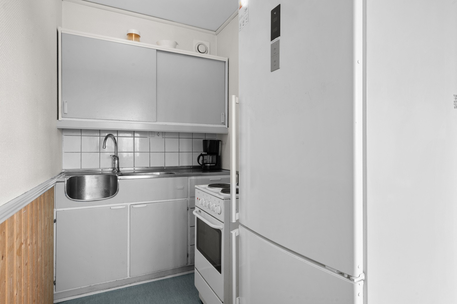 Boligen byr på en praktisk kjøkkenkrok. Innredningen består av glatte fronter, stål benkeplate med vask og frittstående hvitevarer. Galleribilde