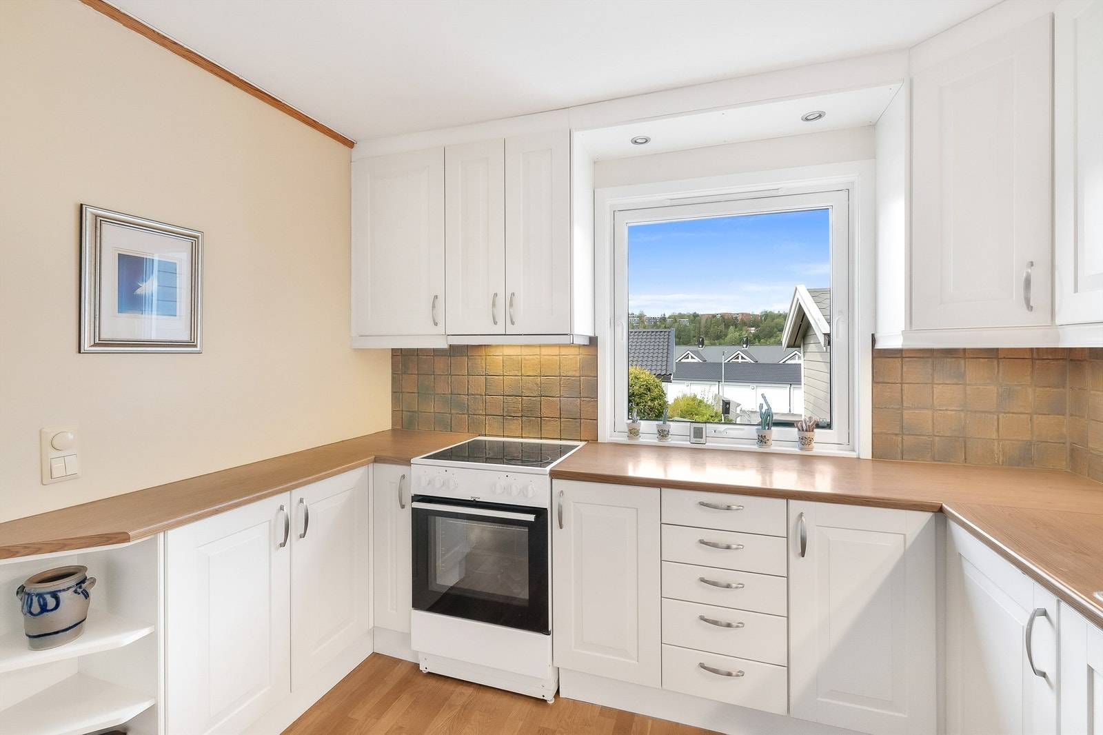 Lys og tidløs innredning med profilerte fronter og benkeplate i laminat med nedfelt vaskekum. Det er rikelig med oppbevaringsplass i både skuffer og skap. Galleribilde