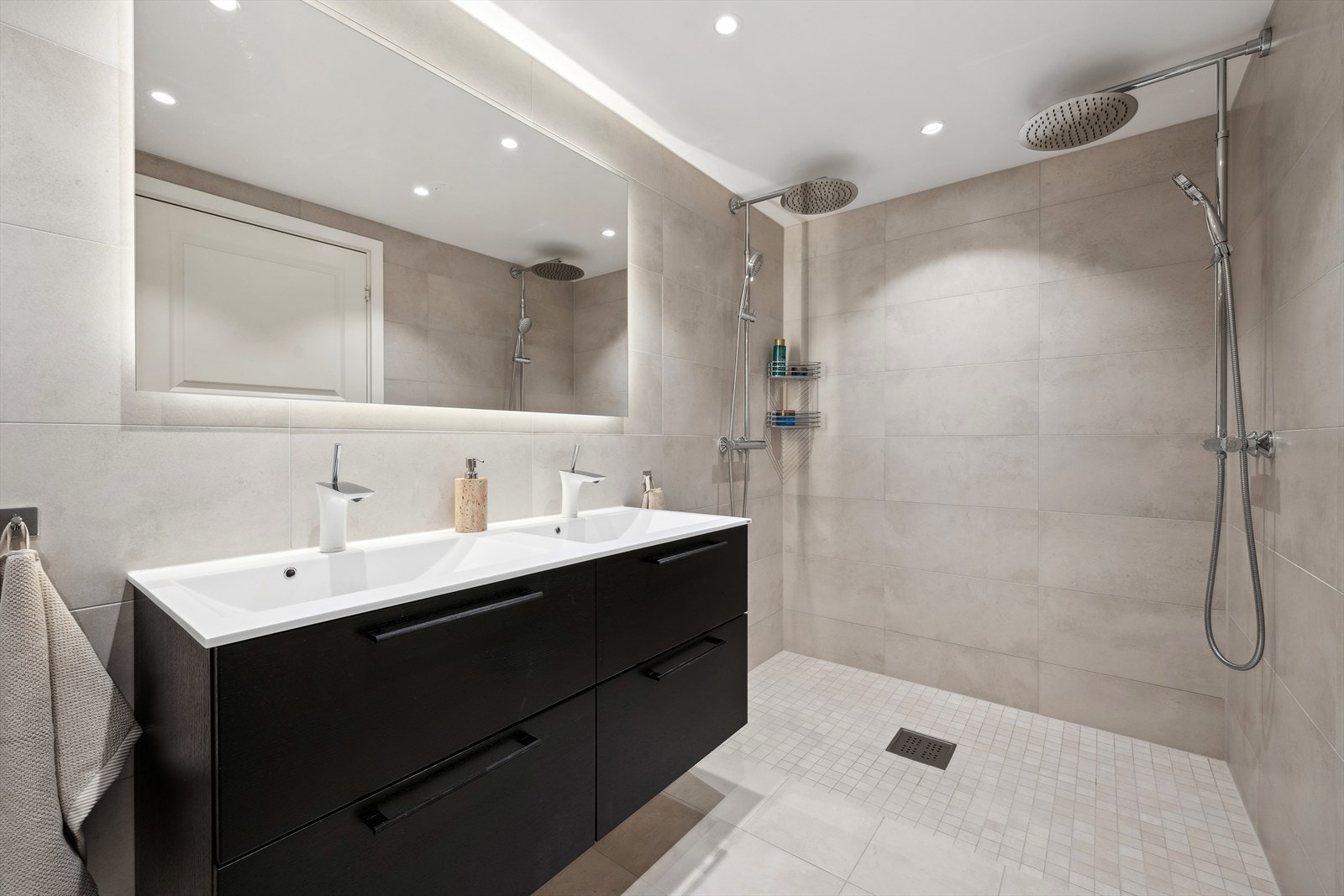 Badet er innredet med servantskap med dobbel servant, 2 stk ett-greps blandebatterier, vegghengt toalett med innebygget sisterne, speil med lys og varme for å fjerne dugg, avskjemet dusjhjørne, innmurt badekar, 2 stk blandebatterier og 2 stk dusjgarnityr. Galleribilde