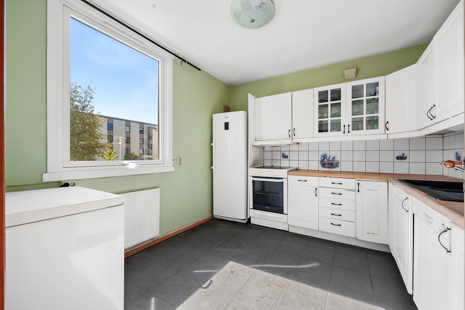 Innredningen har hvite profilerte fronter, vitrineskap og laminerte benkeplater. Galleribilde