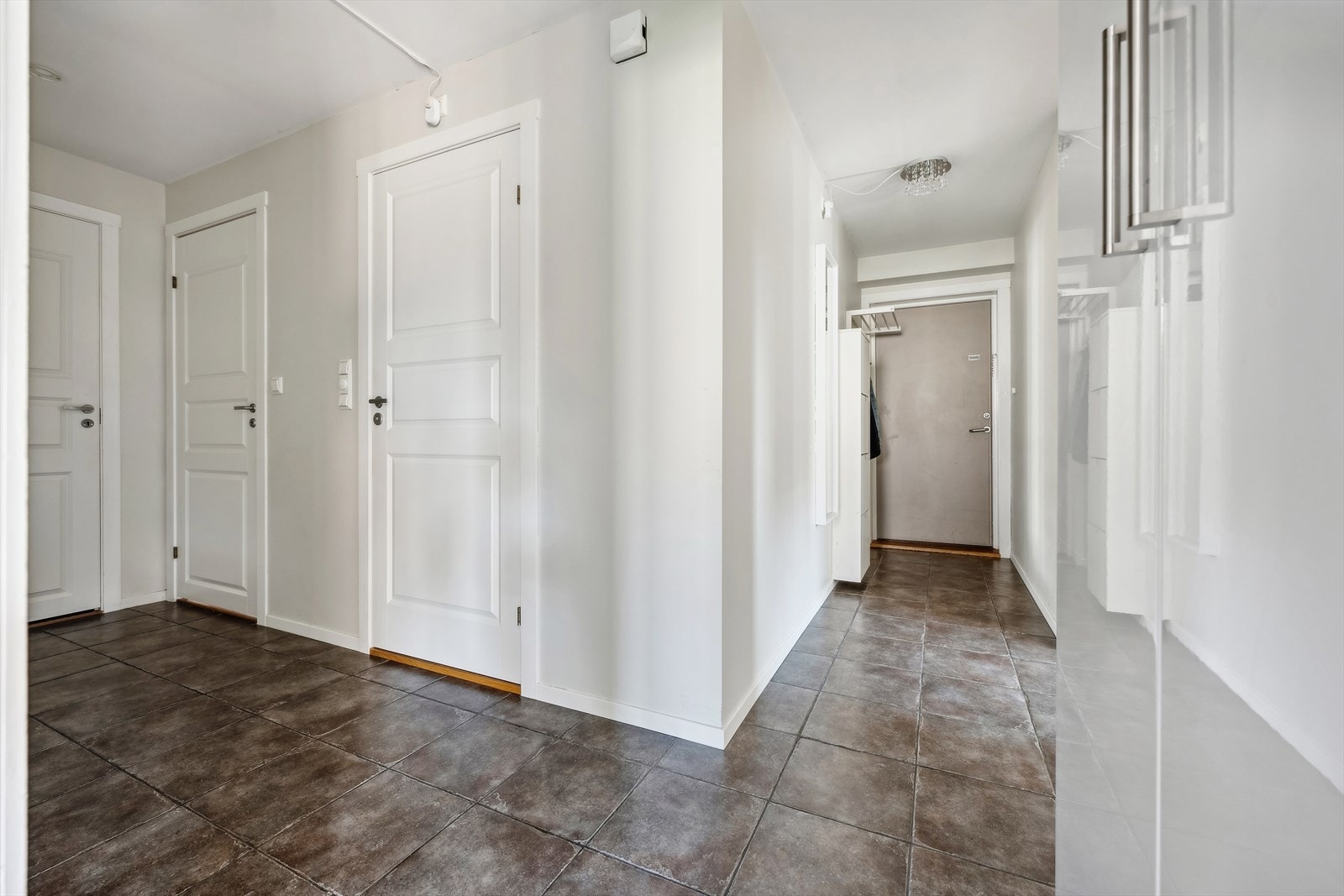 Romslig gang med fliser på gulv, hvor man har god plass til å henge fra seg yttertøy og sko. Galleribilde
