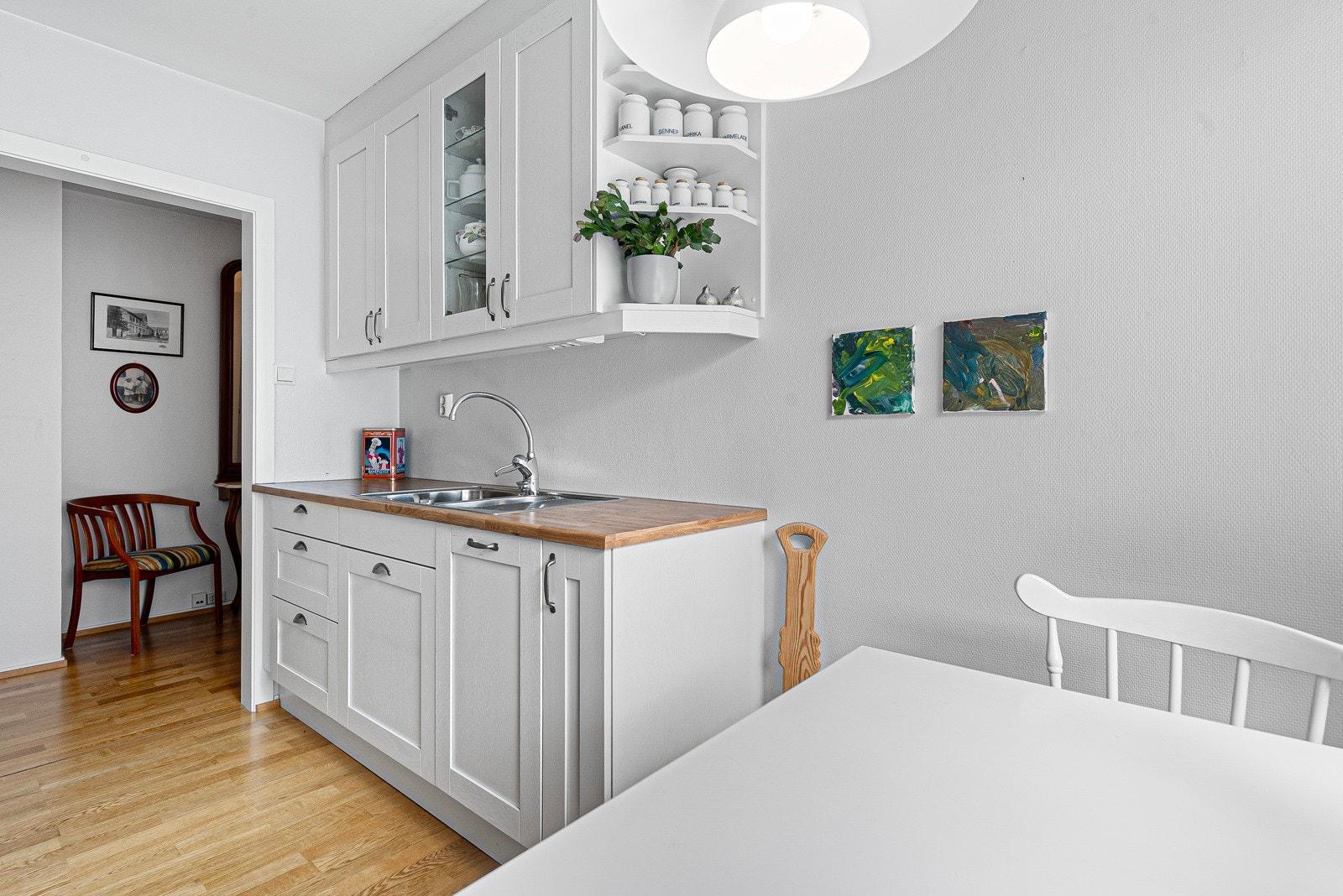 Innredningen har hvite, profilerte fronter, vitrinedører og gyllen laminatbenkeplate med nedfelt kum i stål. Galleribilde