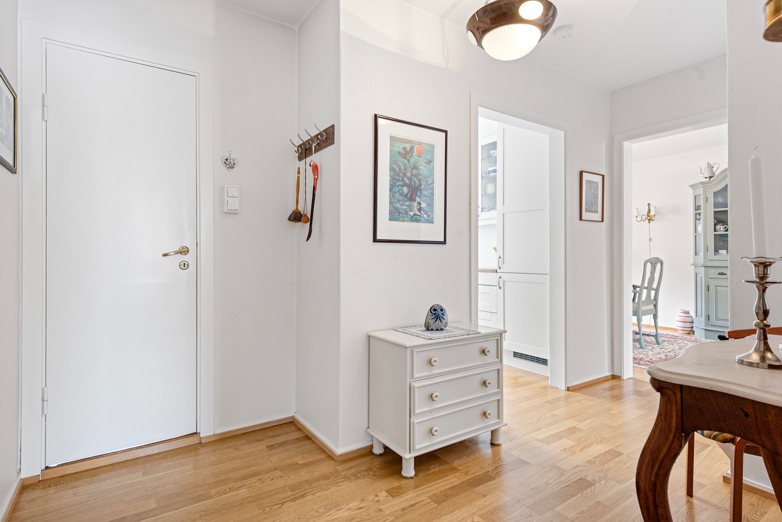 Pen entré med hvitmalte vegger og gyllent, trestavs parkettgulv. Galleribilde