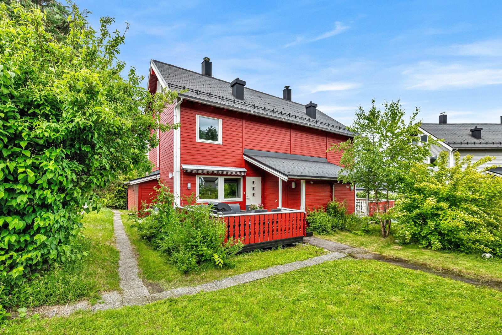 Tomten omkranses av variert vegetasjon med trær og busker, noe som skaper en frodig og naturlig innramming av eiendommen Galleribilde