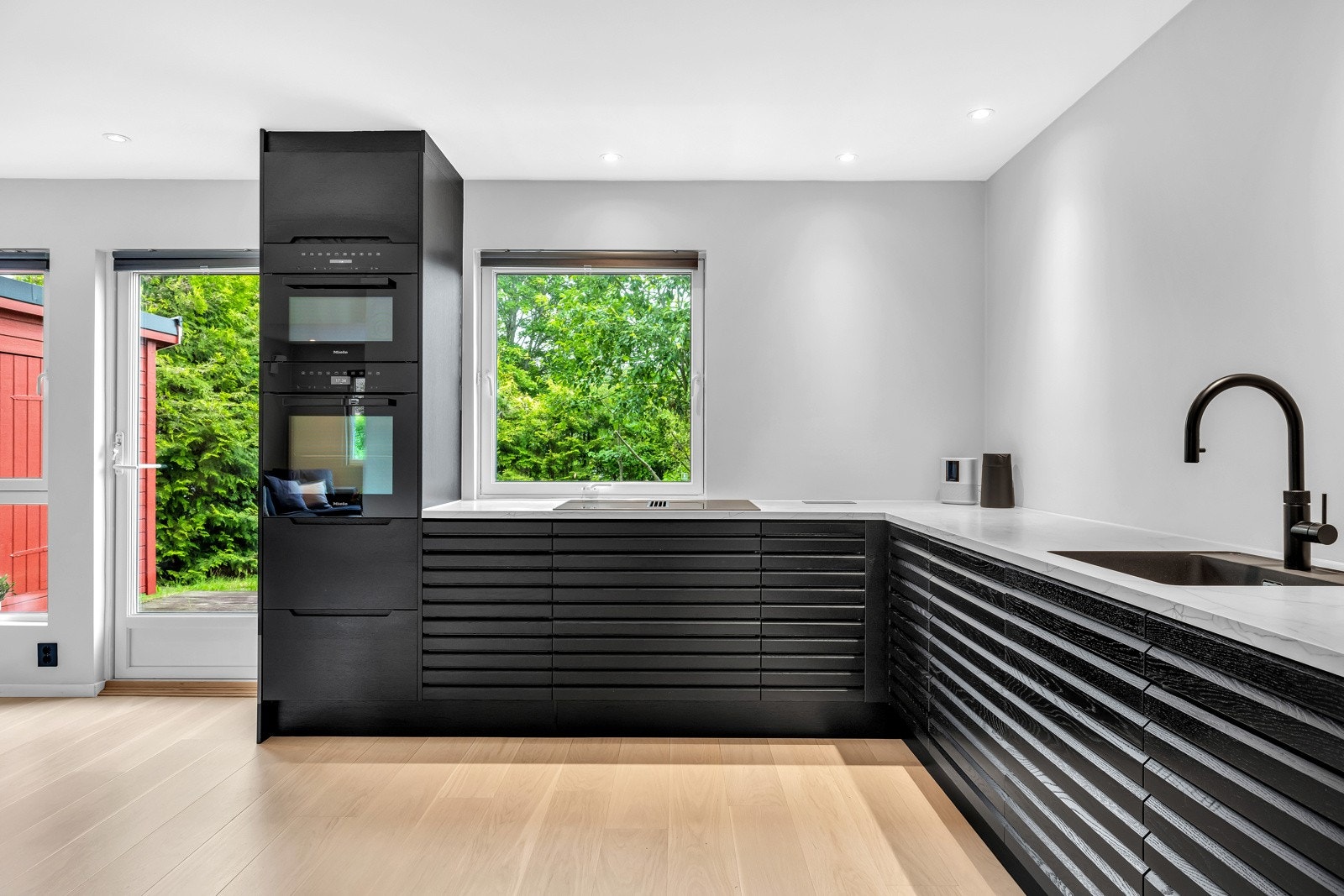 Kjøkkenet er moderne, men likevel tidløst, oppført i en funksjonell L-form med god arbeidsflyt Galleribilde