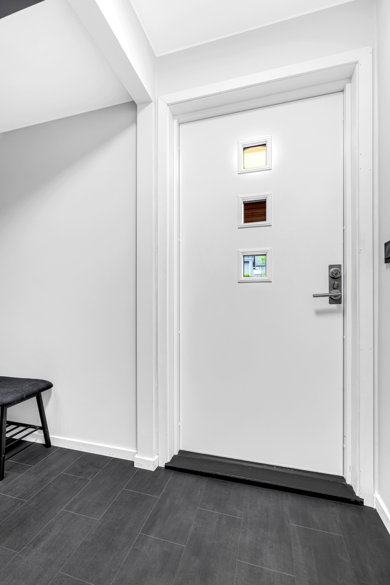 Vel inne ønskes man velkommen av en innbydende entré med gråmalte vegger og mørkt, flismønstret gulvbelegg Galleribilde