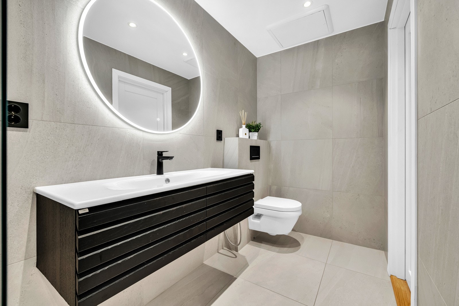 Badet ble pusset opp i 2021 og har store, grå fliser for et delikat uttrykk Galleribilde