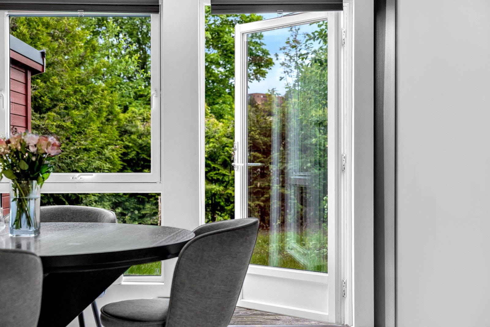 En glassdør fører ut til den usjenerte terrassen på baksiden av huset Galleribilde