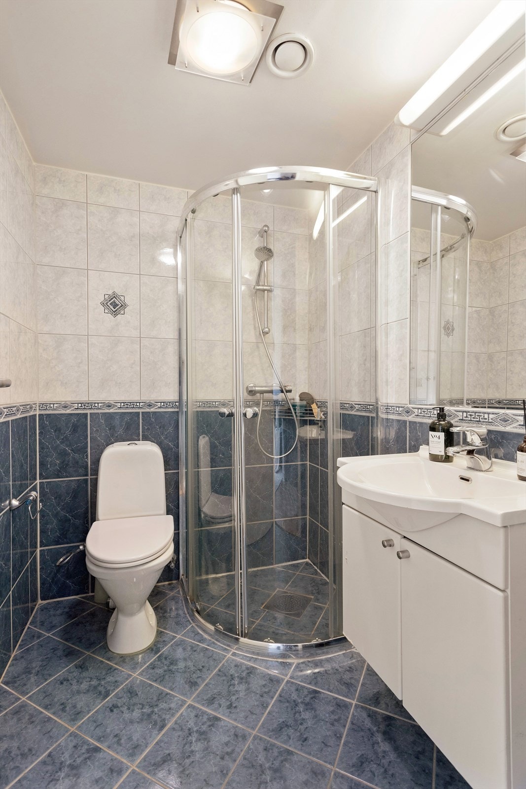 Flislagt bad med gulvvarme, servantskap med ettgreps blandebatteri fra Gustavberg, dusjhjørne og toalett. Galleribilde