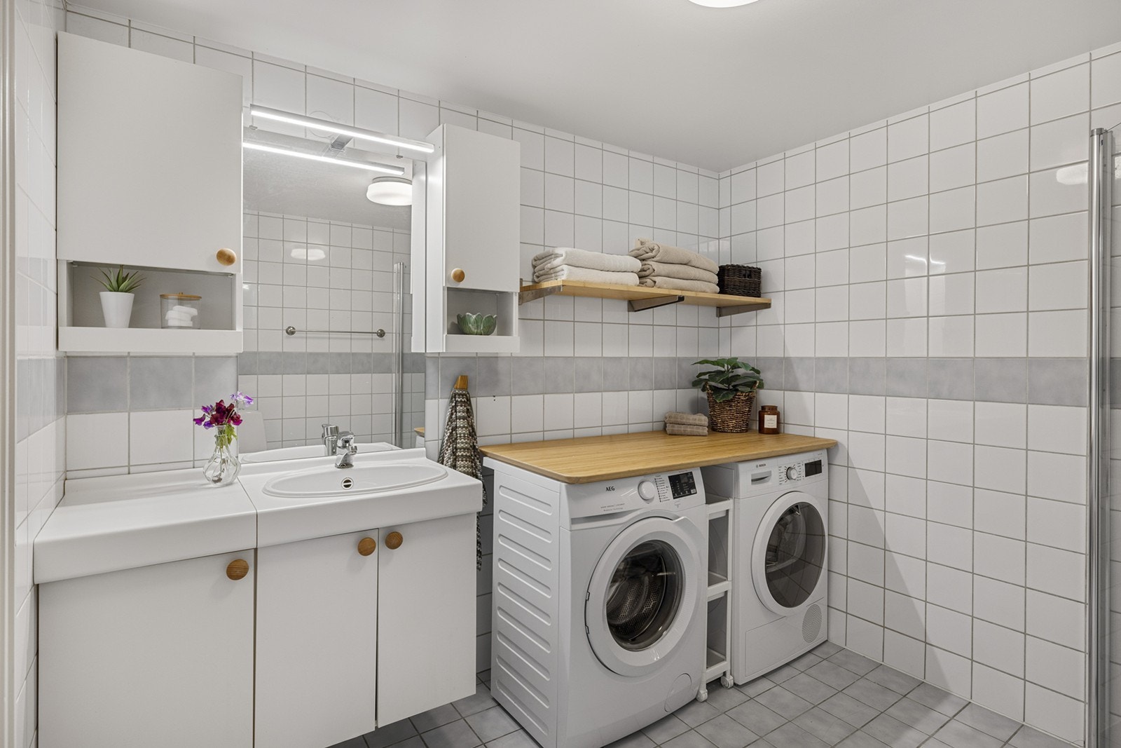 Et romslig flislagt bad med opplegg for vaskemaskin og tørketrommel. Badet har gulvvarme. Galleribilde