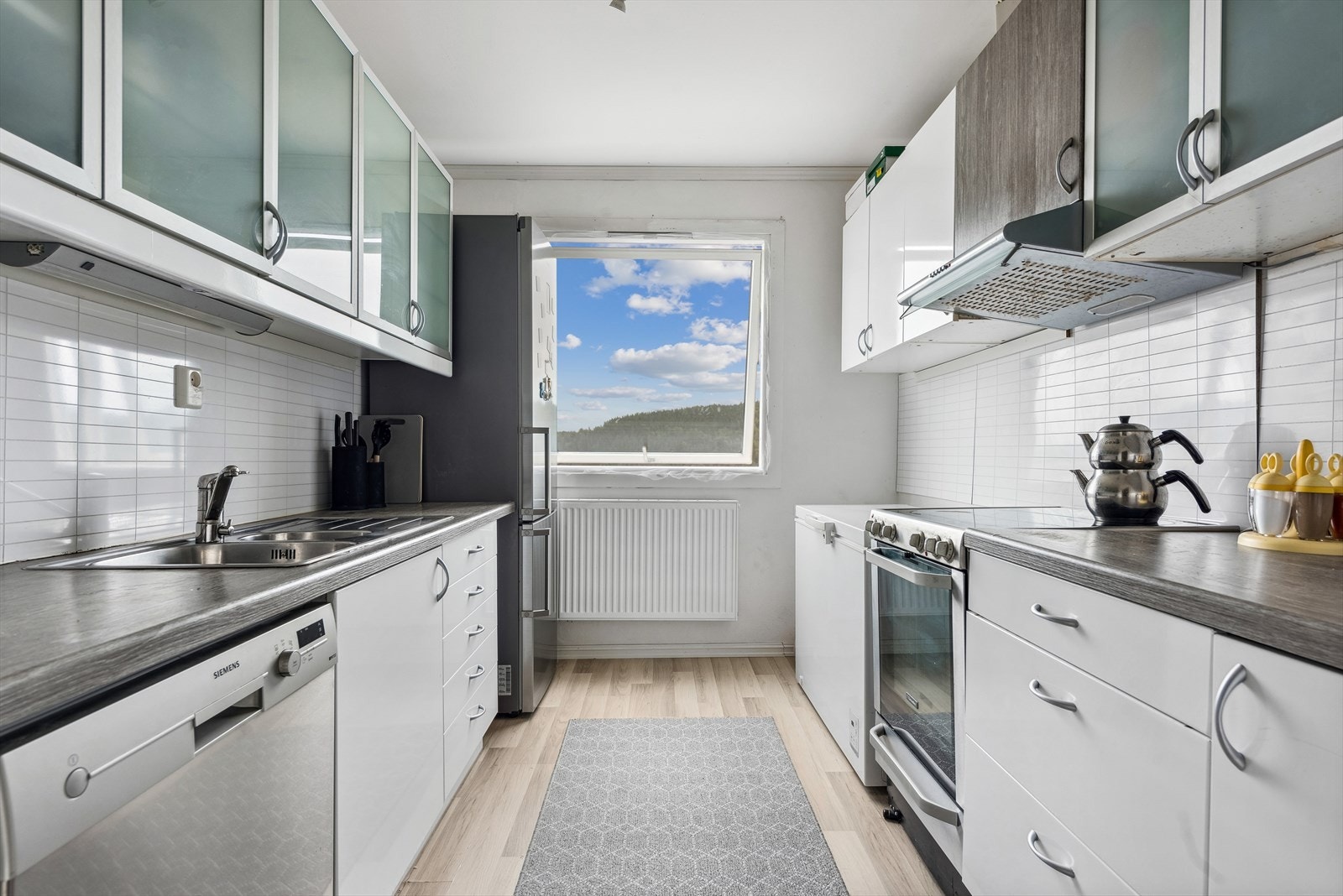 Pen kjøkkeninnredning med hvite fronter, og består av over- og underskap samt skuffer. Galleribilde