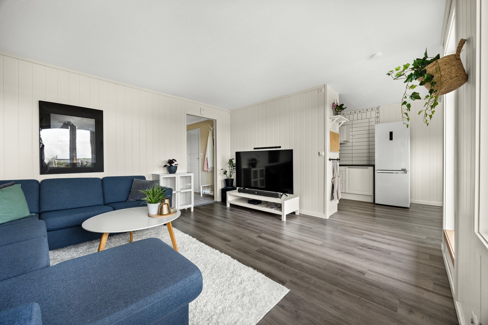 På gulvet er det samme laminat som i entreen, mens veggene er kledd med lysmalte panelplater. Galleribilde