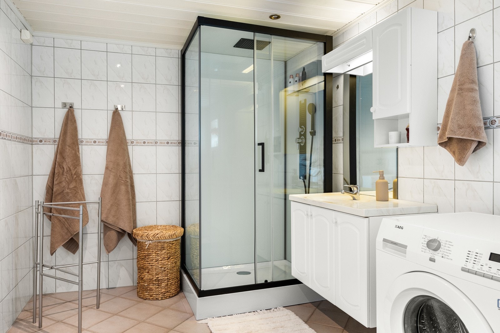 Baderomsinnredningen har hvite, profilerte fronter på over- og underskap, helstøpt servantplate og speil med belysning. Galleribilde