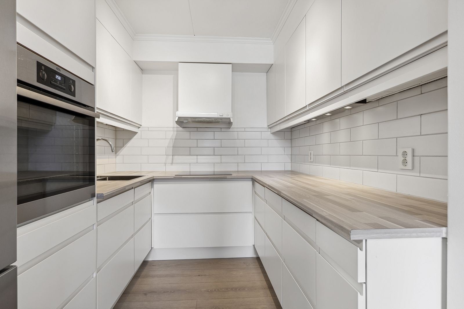 Moderne kjøkken med kombiskap, oppvaskmaskin, komfyr og steketopp. Galleribilde