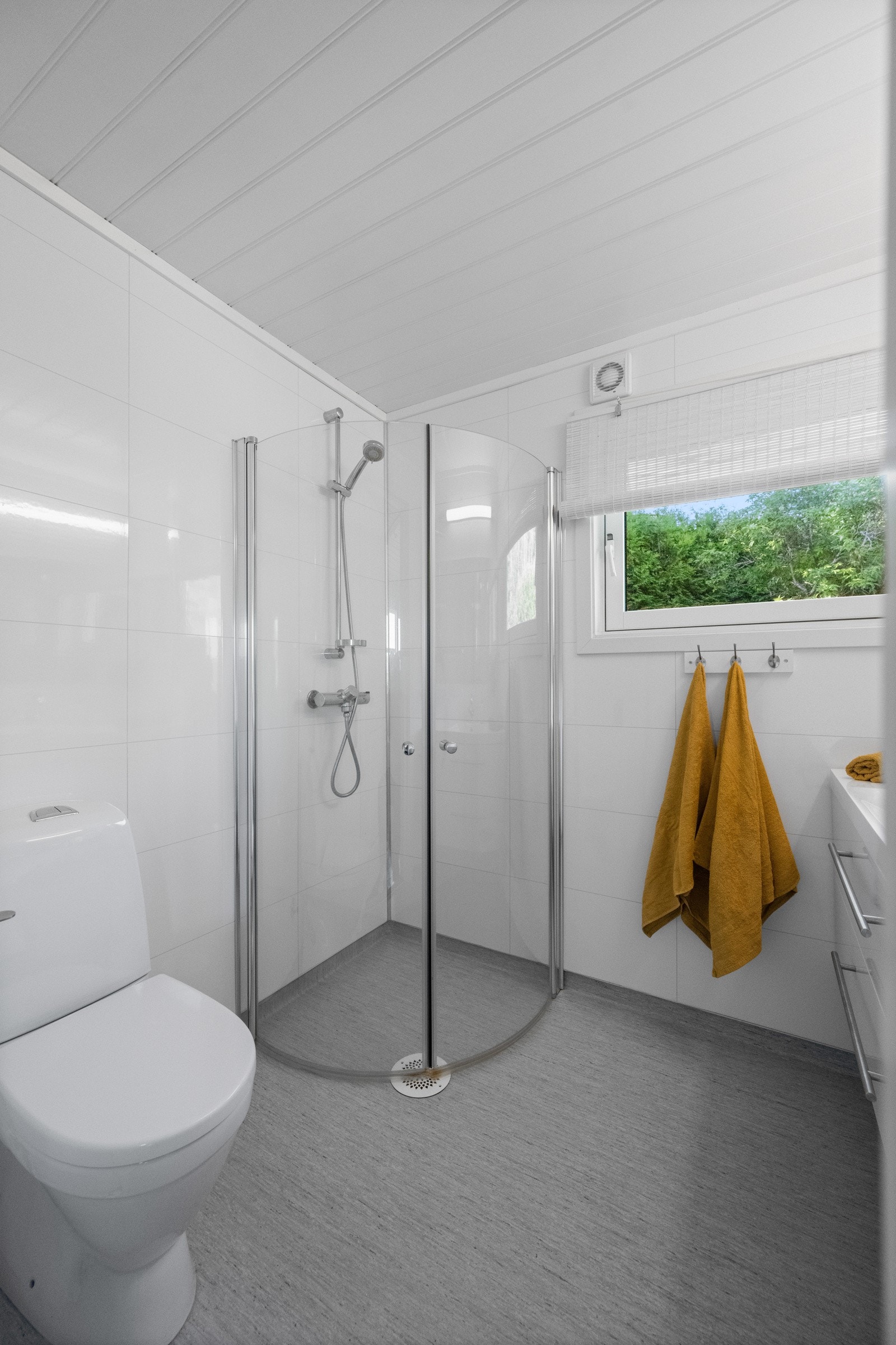 Badet er utstyrt med servent med underskap, dusjvegger og gulvmontert wc. Galleribilde