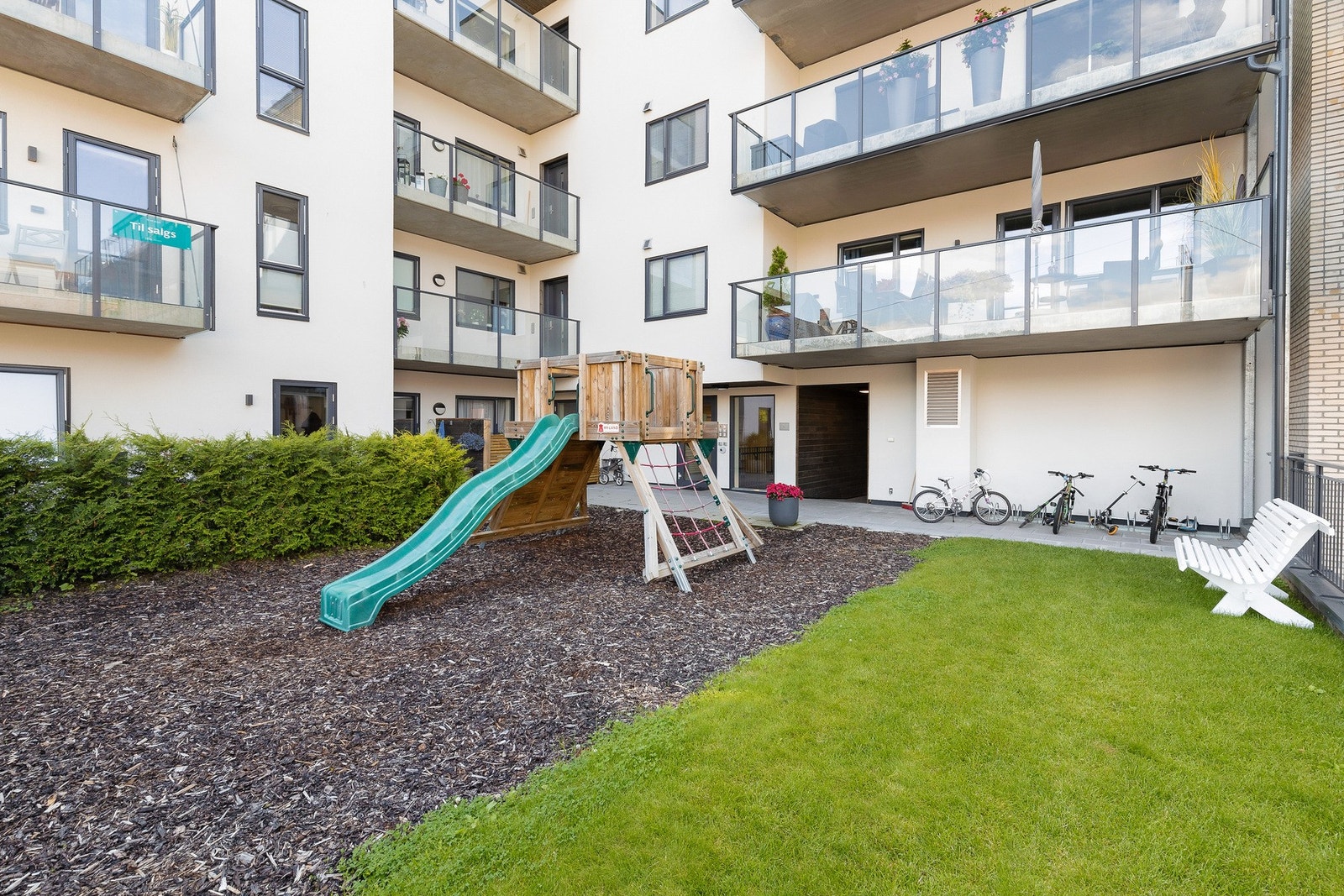 Pent opparbeidet felles tomt med lekeplass, plen og sittebenker Galleribilde