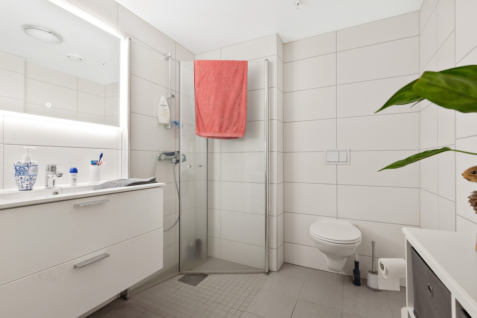 Leiligheten har et delikat og helfliset bad med vegghengt toalett og nedsenket dusjhjørne med glassdører Galleribilde