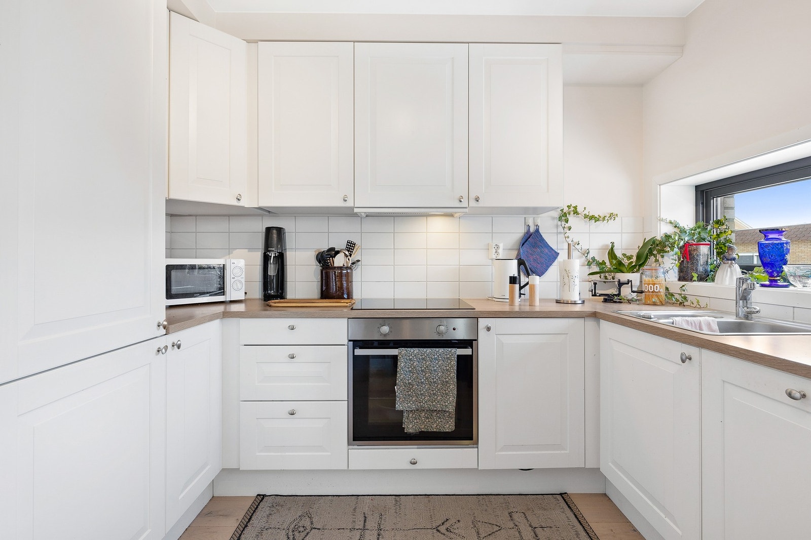 Pen kjøkkeninnredning med hvite profilerte fronter og laminat benkeplate Galleribilde