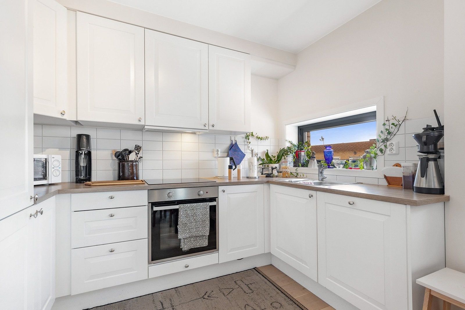 Innredningen har integrerte hvitevarer, herunder oppvaskmaskin, platetopp, komfyr og kjøleskap med frys Galleribilde