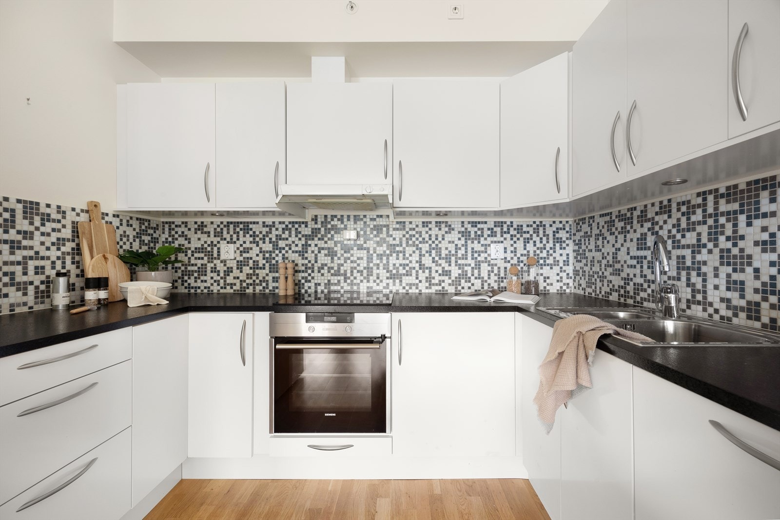 Norema kjøkken av god standard med hvite slette fronter, laminat benkeplate og mosaikkfliser bak. Galleribilde