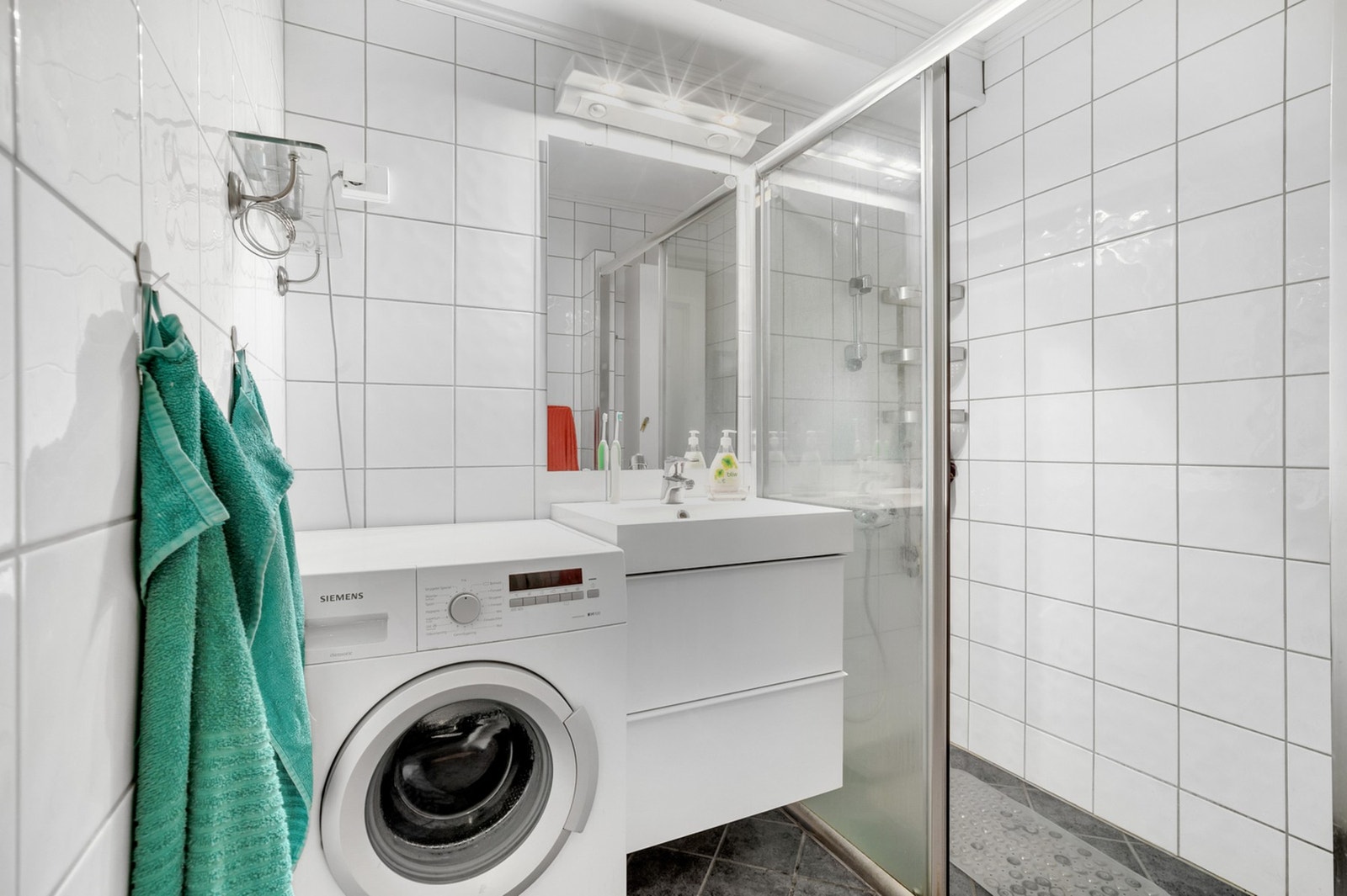 Lyst bad med varmekabler i gulvet og opplegg for vaskemaskin. Galleribilde