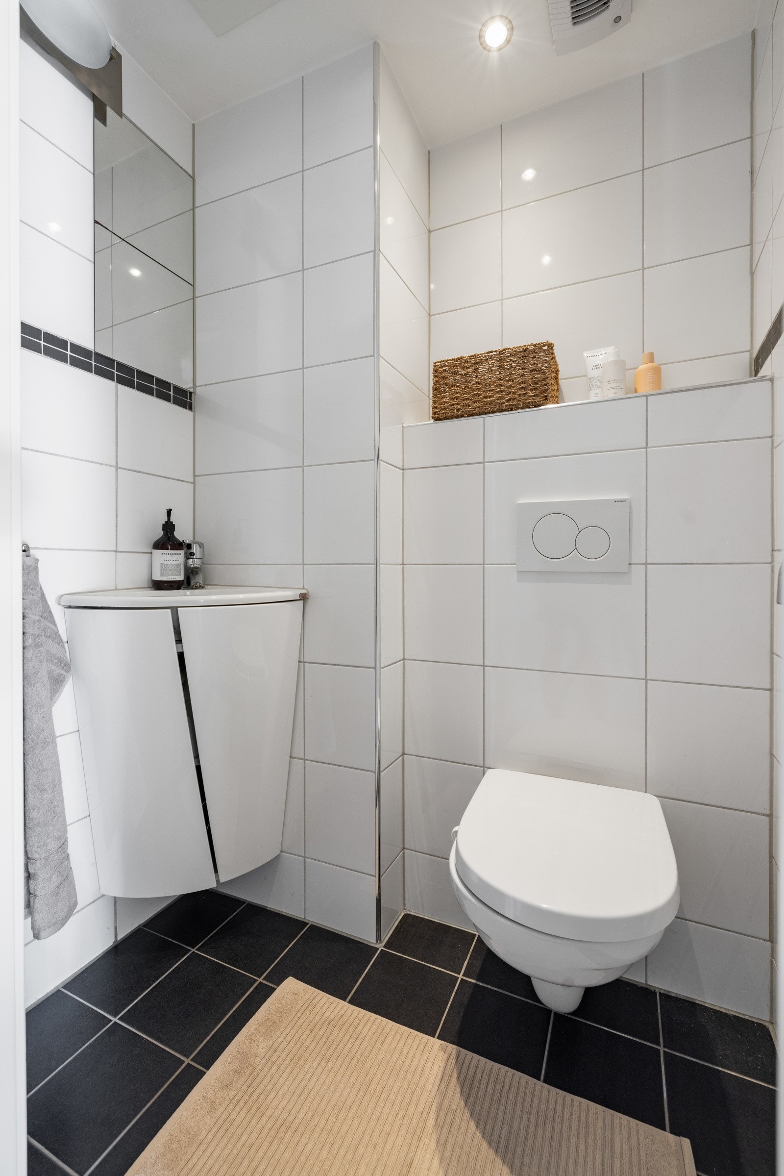 Vegg i vegg ligger et praktisk separat toalettrom med vegghengt toalett, servant med underskap og speil. Galleribilde