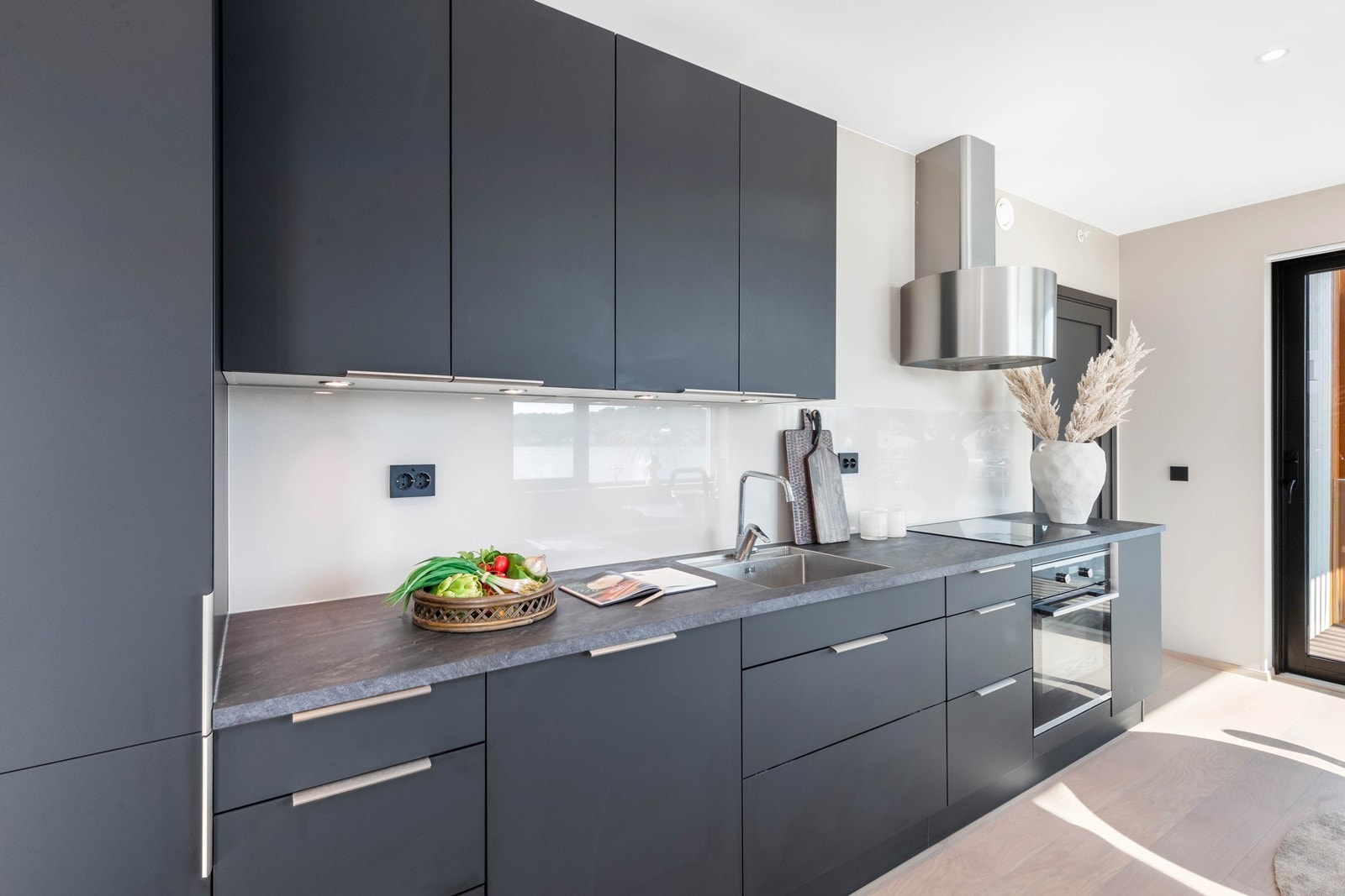 Integrerte hvitevarer som kombi kjøl/fryseskap, koketopp med induksjon, komfyr og oppvaskmaskin. Galleribilde