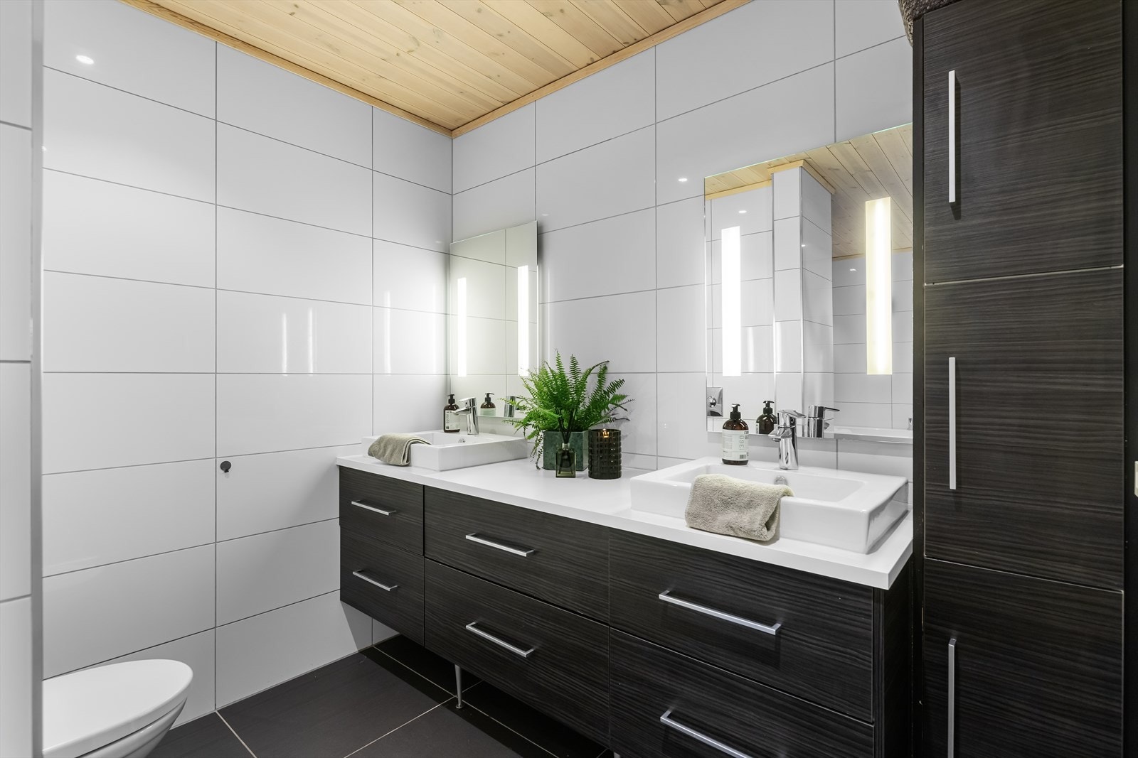 Innredning i mørke toner og dobbel servant med overhengt speil med integrert lys! Galleribilde